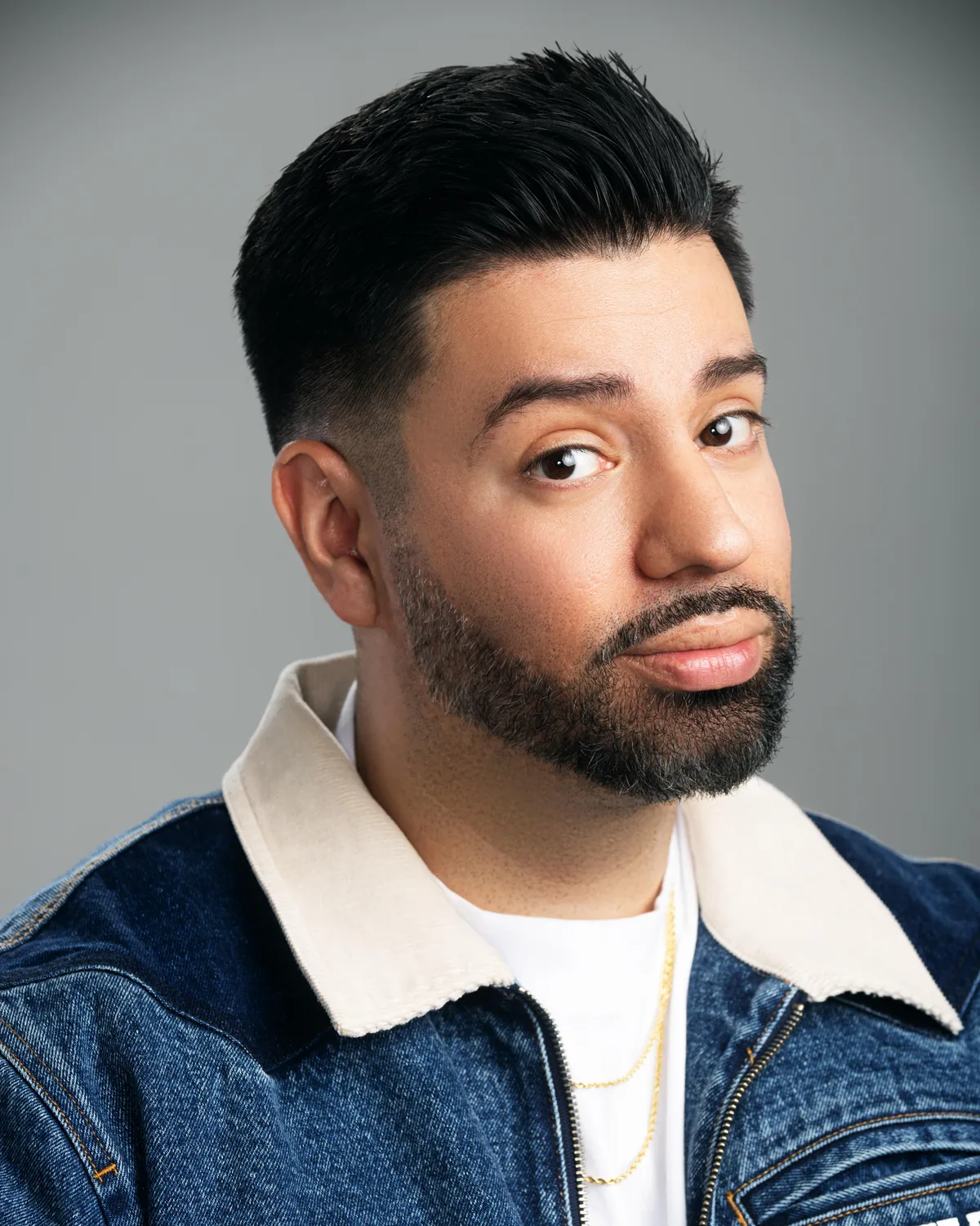 Martin Amini in a denim jacket, eyebrow raised