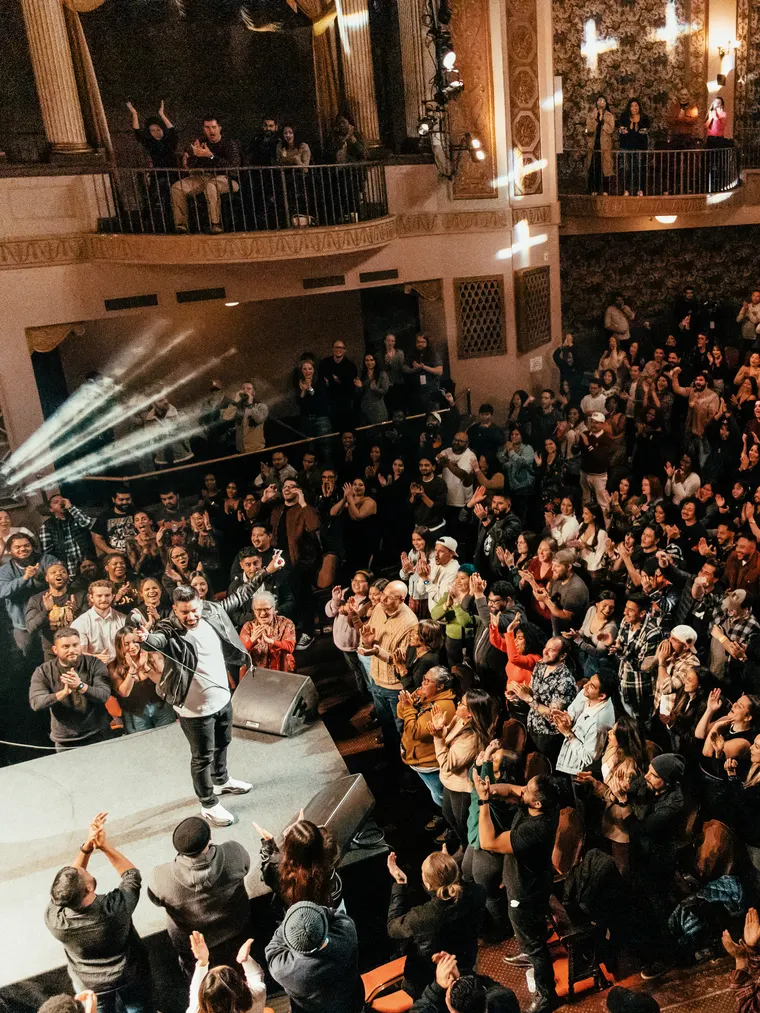 Martin Amini on stage in front of a packed, standing theatre crowd